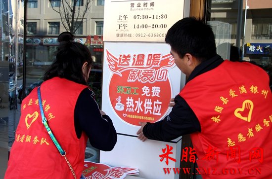 图为志愿者正在粘贴爱心供水点标识